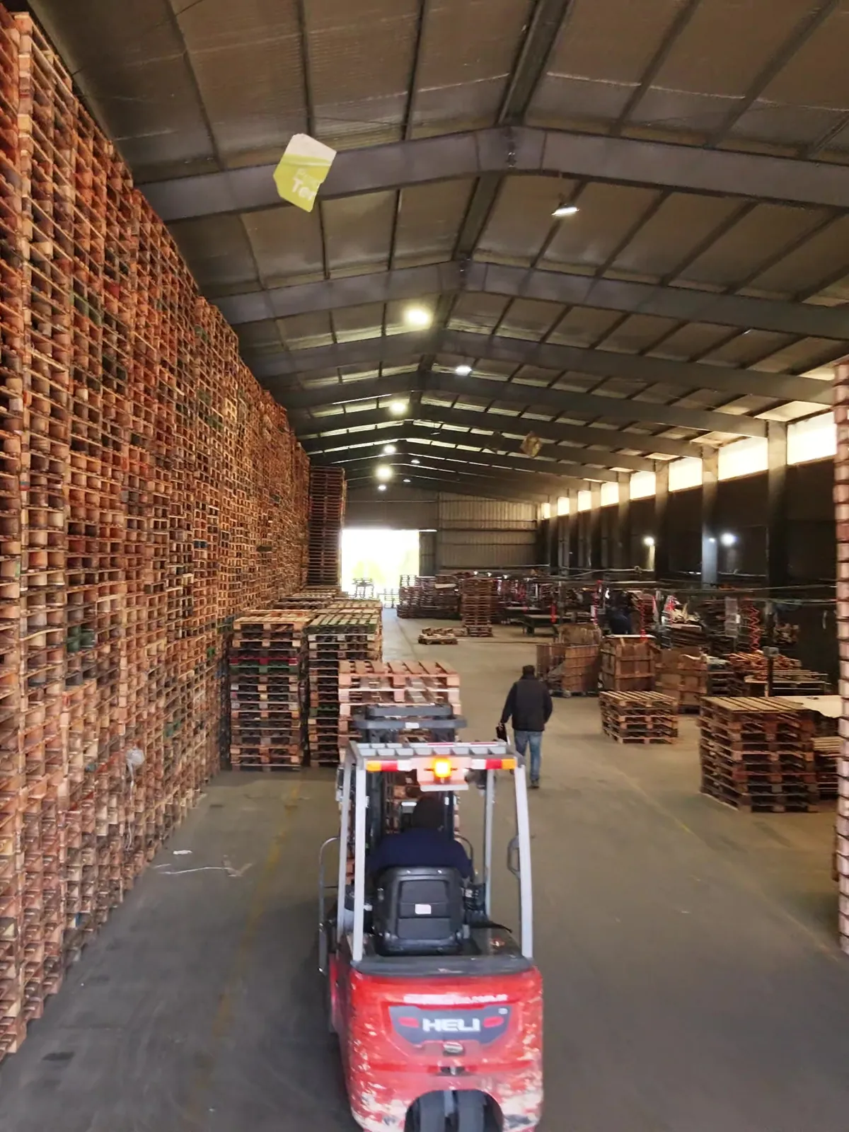 Autoelevador avanzando entre paredes de pallets apilados en una nave de Transpallets