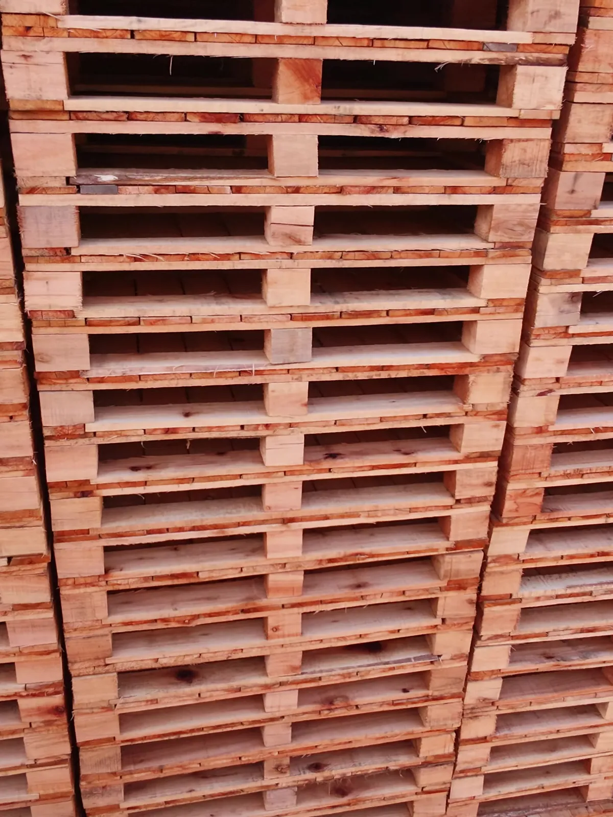 Pila de pallets de madera vista de cerca, en una nave de Transpallets